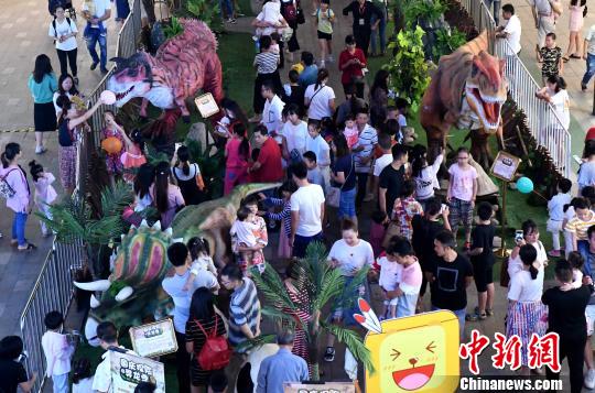 图为一组大型仿真恐龙模型亮相福州一商场，吸引了许多市民带着小孩前来观赏抚摸。　张斌 摄